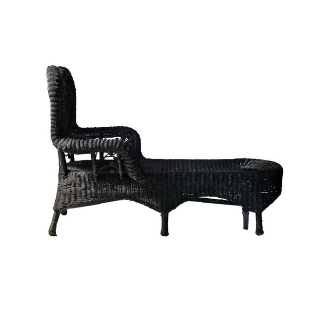 Antique Victorian wicker chaise lounge featuring an ornate, high fan-back style and a dramatic black painted finish. This...