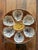 Ceramic oyster plate with six shell-form wells surrounding a central sauce well, glazed in a mottled, running brown glaze...