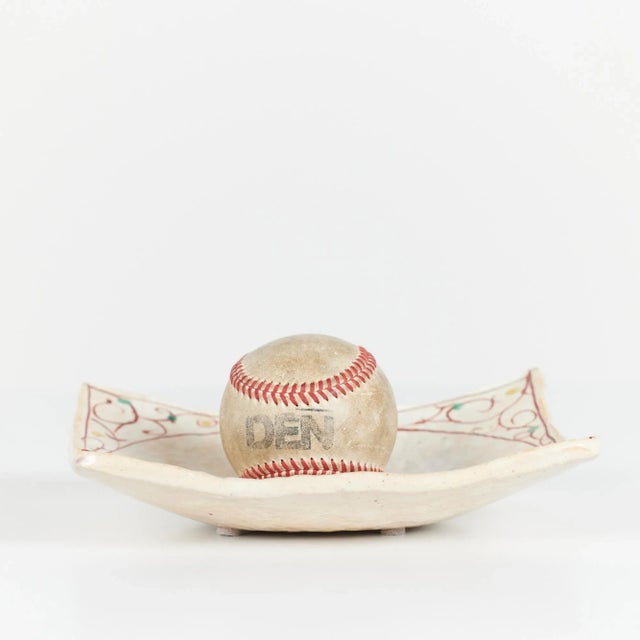 Ceramic plate features a square shape with turned up corners. The plate is glazed in a soft cream and beige coloring with...