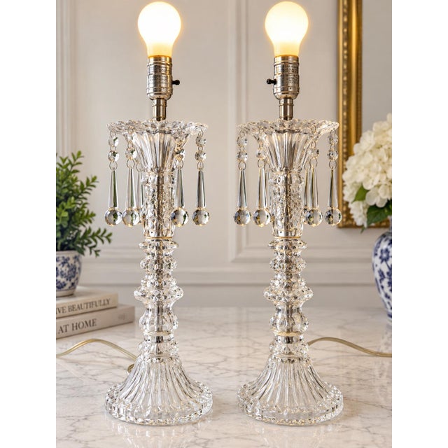 Elegant vintage pair of clear cut-glass table lamps featuring beautifully sculpted decorative bodies and cascading faceted...