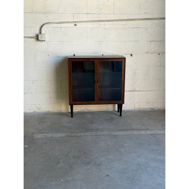 Sleek architectural form meets clean minimalist lines in this striking storage piece. Two tall glass doors swing outward...