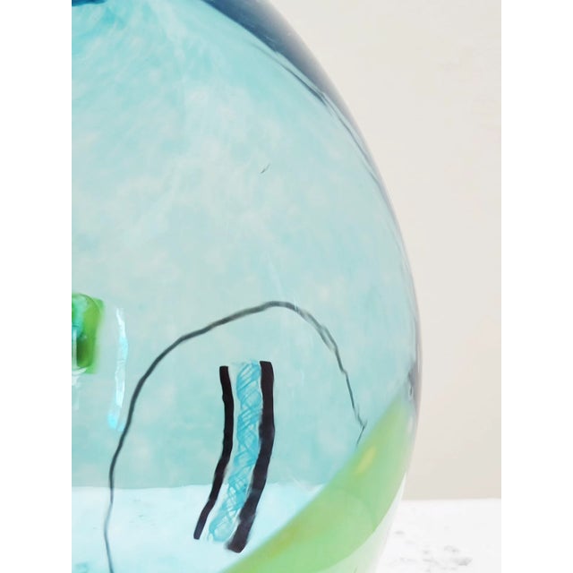 Luminous confetti glass 7" spherical vase by Pizzichillo + Gordon in blue with accents in red, orange, yellow, and black....