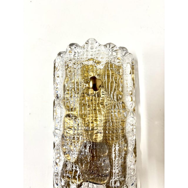 Sconces in brass with shades of pressed glass. Designed by Carl Fagerlund for Orrefors, 1960s. This piece has an...