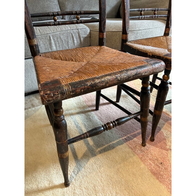 Charming pair of vintage ladderback chairs featuring hand-woven rush seats, turned legs, and classic Early American...