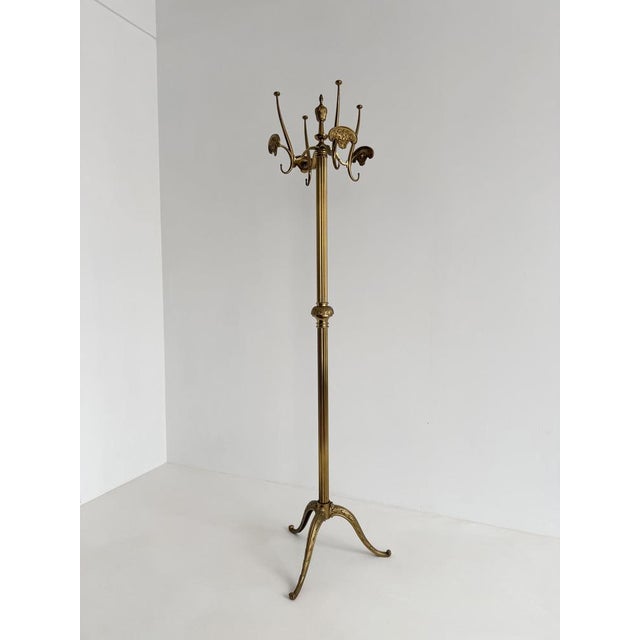 Elegant vintage brass coat rack featuring a smoothly rotating crown, richly decorated hooks, a refined fluted column, and...