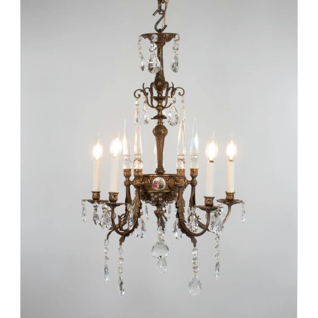 This early 20th-century five-arm Rococo-style bronze and crystal chandelier features porcelain plaques inspired by the...