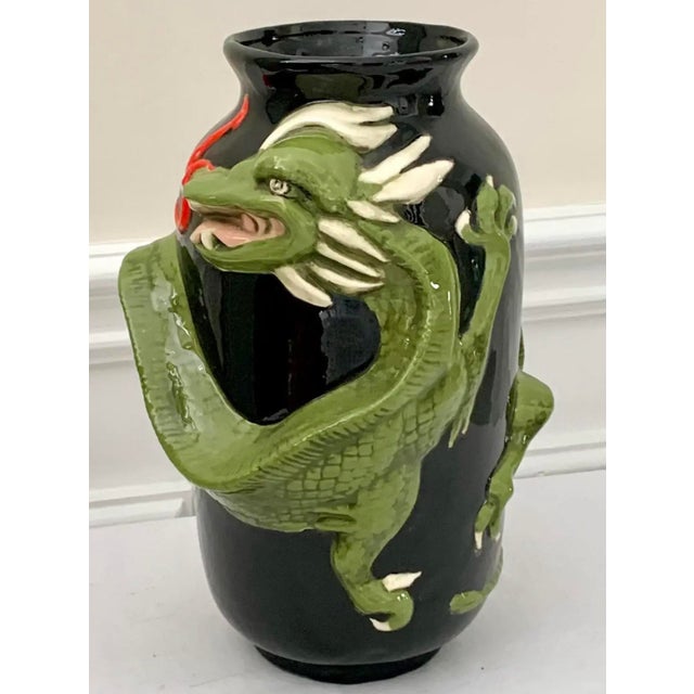 Striking sculptural ceramic vase featuring a bold green dragon in high relief, coiled around a glossy black body. The...