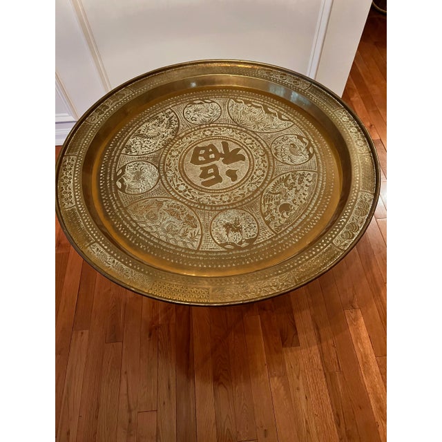 Antique Asian handcrafted brass tray table, circa 1920-30s. The tray is engraved with varying intricate hand carved floral...
