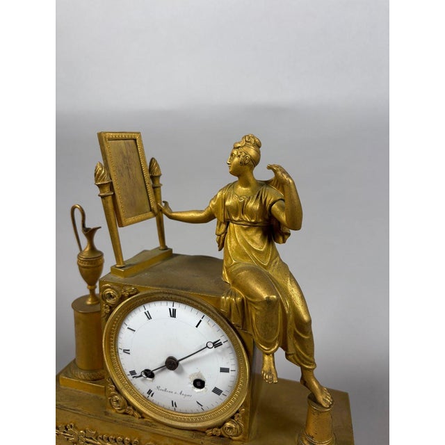 A gilt bronze clock depicting a young woman at her toilette. French work, Empire period, circa 1800. Gilt bronze, polished...