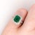 An emerald shines in a rich green at the heart of this solid 14K white gold ring, framed by 102 earth-mined diamonds....