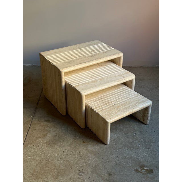 A set of three nesting side tables in solid travertine, designed in a stepped form typical of postmodern furniture. Each...