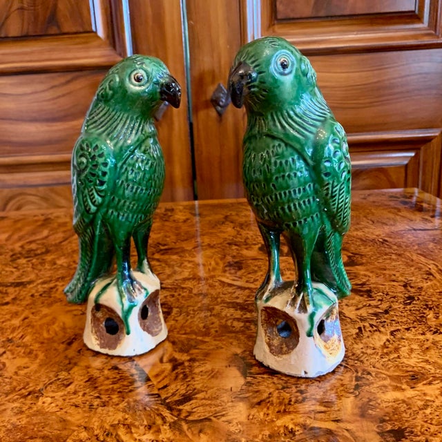 A delightful pair of green glazed Chinese Export earthenware parrots standing on bits of rockery glazed in pale ochre with...
