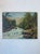 This vintage landscape painting presents a vibrant depiction of a mountain stream tumbling over rocks, surrounded by dense...
