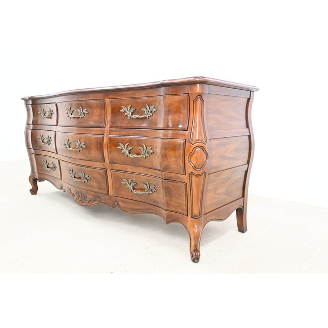 This refined vintage dresser by John Widdicomb is crafted in rich cherry wood and showcases a gracefully bombe silhouette...