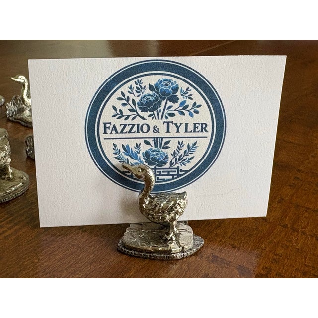 Elevate your table with a touch of quiet luxury: a complete set of 12 vintage pewter duck place card holders, crafted in...