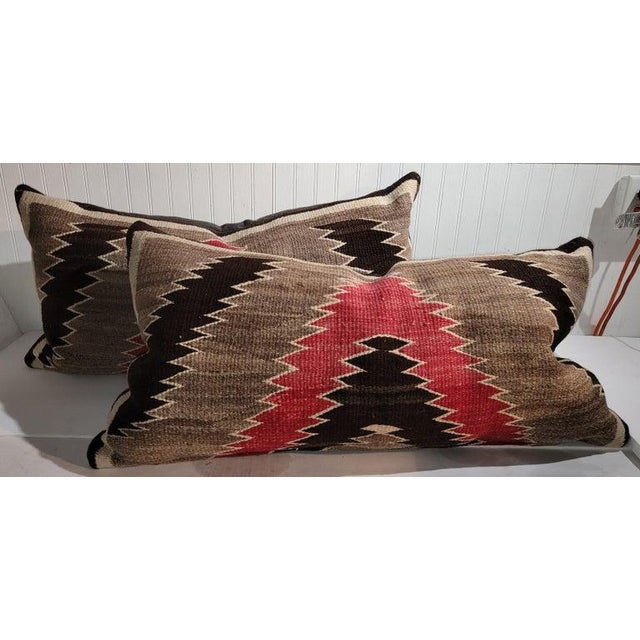Collection of three wool weaving geometric bolster pillows. The backings are in brown cotton linen & down & feather...