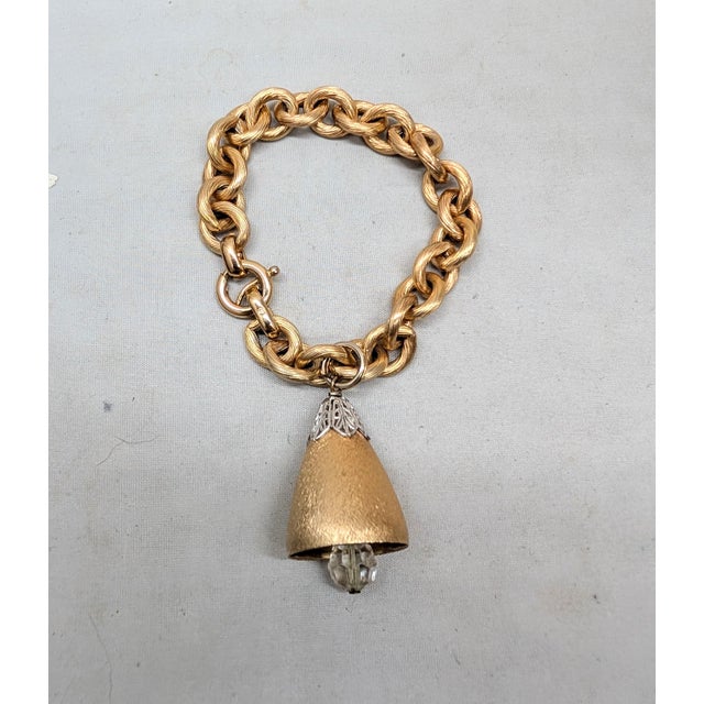 Goldtone Florentine finish bell charm with a faceted glass clapper with a rhodium plated filigree cap at the top on a...