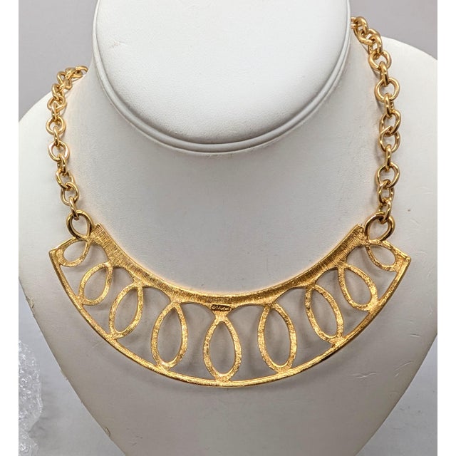 1980s goldtone looped bib necklace on a chain with hook clasp. Marked "©MONET" on the back of the bib section. Measures: 8...