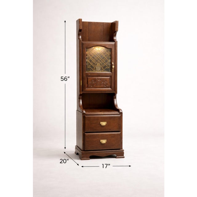 A rare early 20th-century solid oak gentleman’s bedside cabinet with leaded glass door, carved detailing, and original...