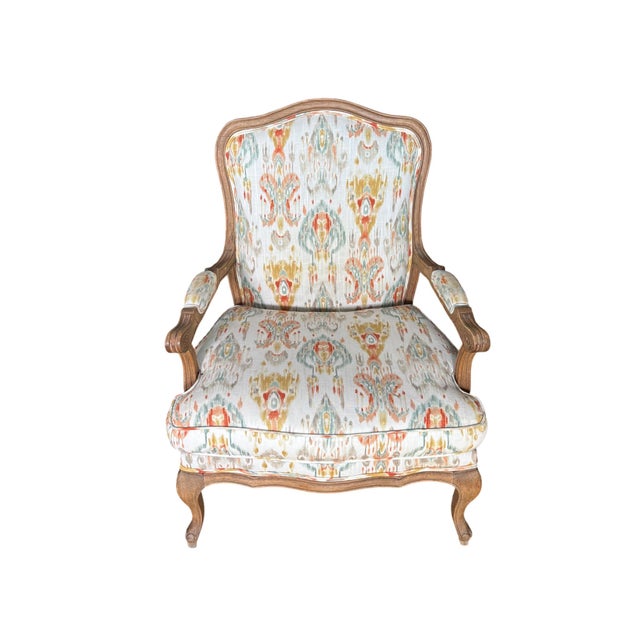 A French Provincial armchair in the Louis XV idiom, with a hand-carved oak frame in a natural, finish. The shaped crest...