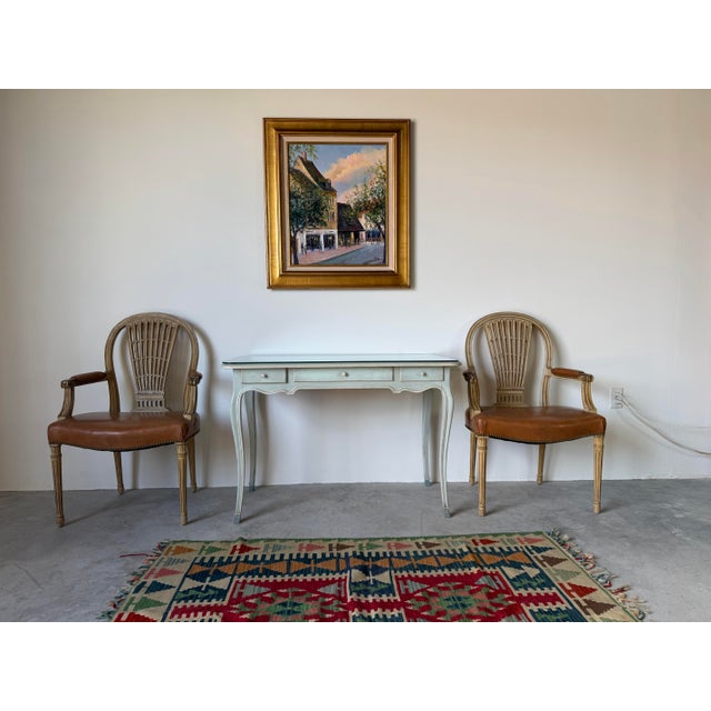 Elegant pair of Hollywood Regency armchairs inspired by the iconic Maison Jansen Louis XVI aesthetic. Featuring graceful...