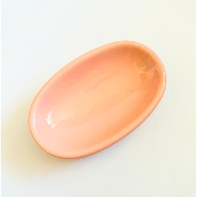 A vintage 1980s ceramic soap dish. Simple oval shape, finished in glossy light pink glaze. Embossed detailing along the...