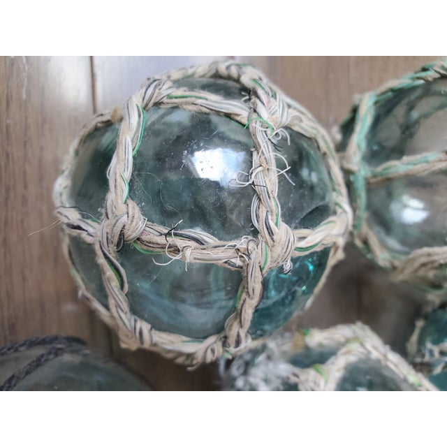 Set of 5 antique fishing floats made of mouth-blown blue glass. The cotton net originally woven around the floats is soft...