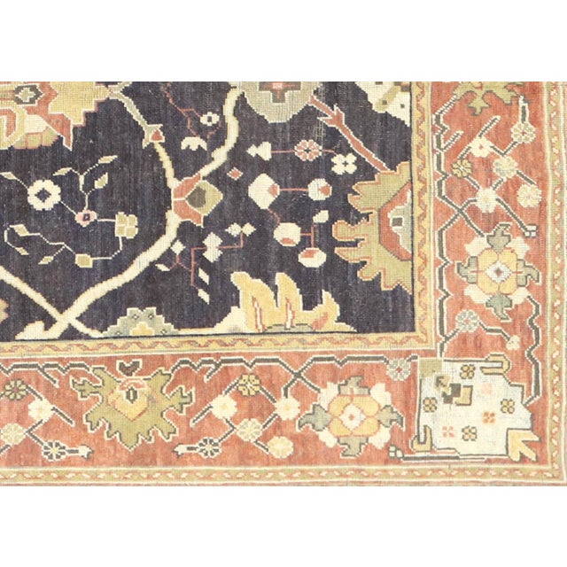 This semi-antique Turkish Oushak rug, measuring 11'4" by 13'9", is meticulously handwoven with wool on a wool foundation...