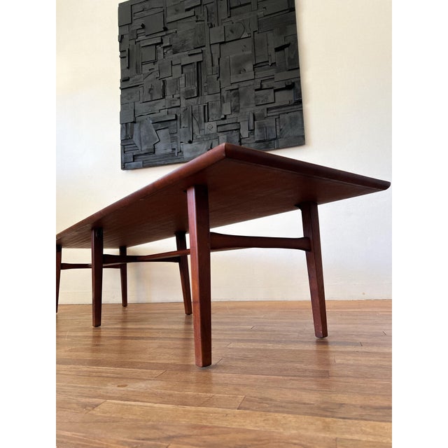 A refined Mid-Century Modern walnut platform coffee table featuring a long rectangular top, tapered legs, and a...