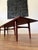 A refined Mid-Century Modern walnut platform coffee table featuring a long rectangular top, tapered legs, and a...