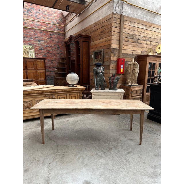 This antique solid oak farmhouse table has been fully restored. It features a beautiful raw wood top and tapered legs....
