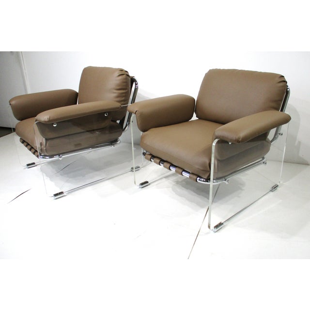 A pair of rare, sophisticated, upholstered leatherette and Lucite lounge chairs with large arms and loose cushions for...