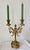 Delicate and refined candlestick with two arms of light. Its base is wide, supported by four cushion feet. The shaft is...