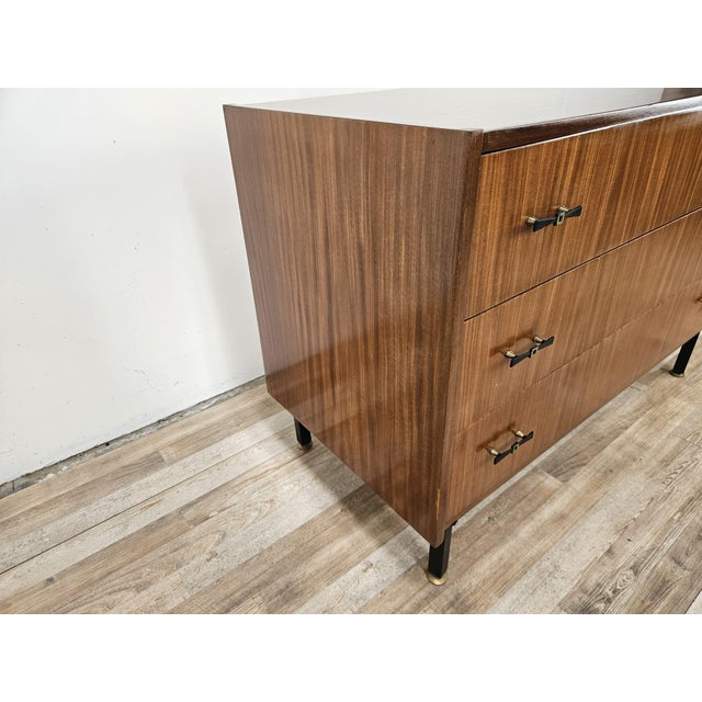An elegant small chest of drawers dating back to the 1960s, characterized by clean lines, compact proportions, and the...