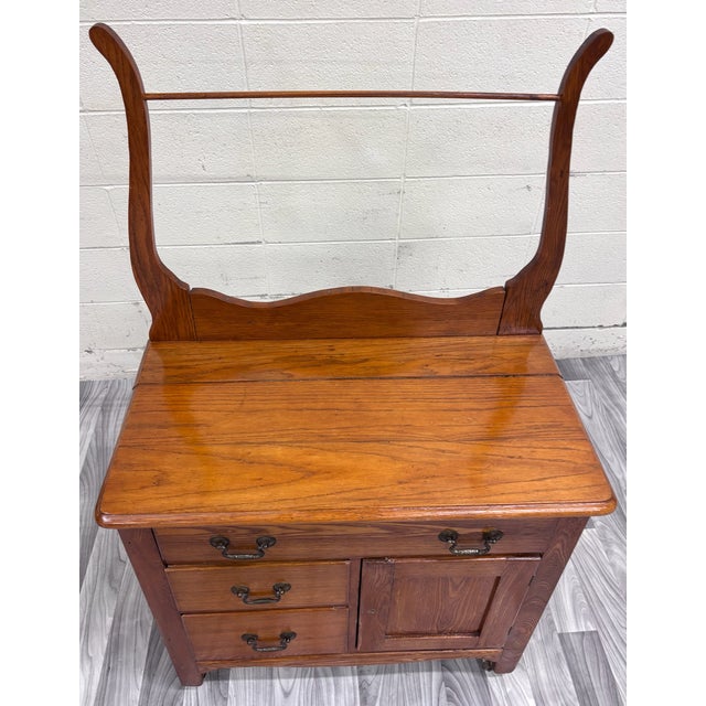 This is a gorgeous antique Victorian oak washstand featuring a shaped backsplash, tall towel rack, three drawers with...