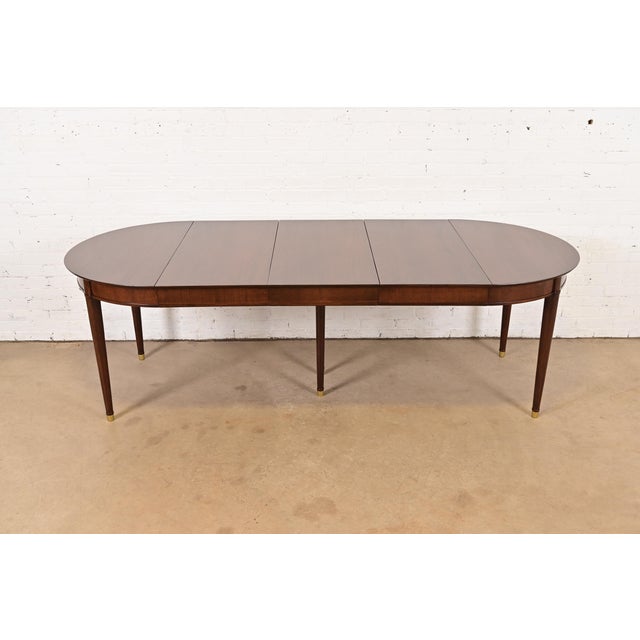 A beautiful French Regency Louis XVI style extension dining table By Henredon USA, Circa 1970s Gorgeous walnut, with brass...