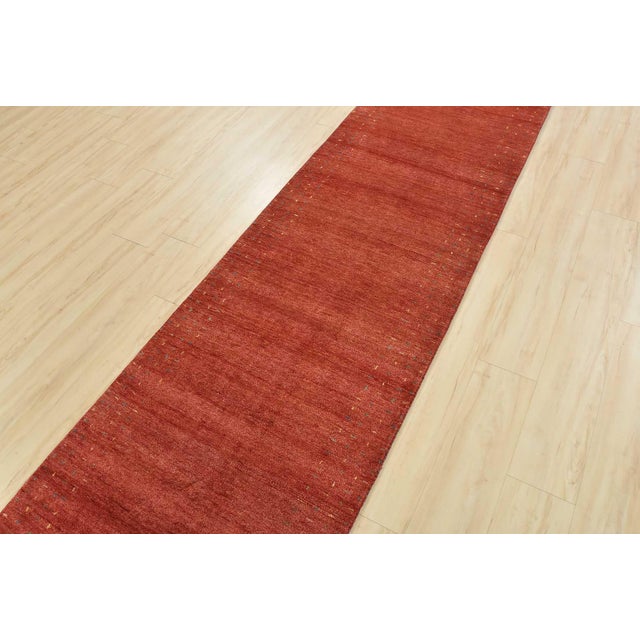 A contemporary Gabbeh runner hand-knotted with an all-wool pile on a cotton foundation. This oriental rug features a solid...