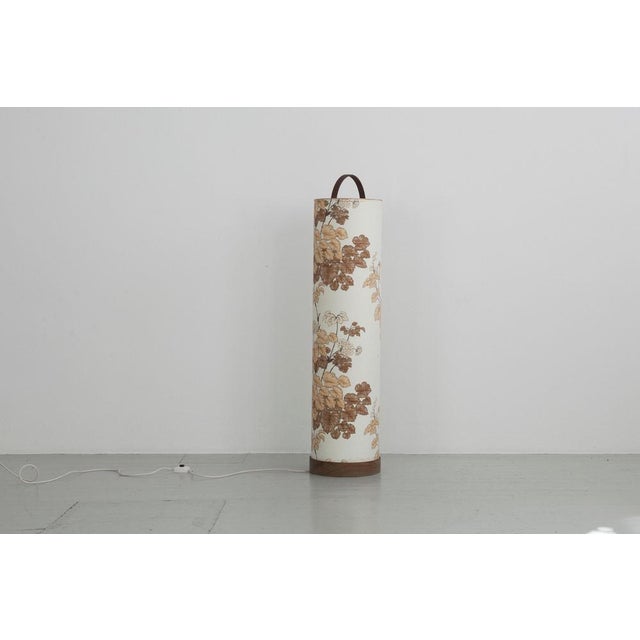 Cylindrical floor lamp from the 70s. The lampshade is continuous to the floor and covered with a floral fabric. The base...