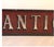 A long, narrow trade sign reading "ANTIQUES" in raised, silver gilded serif letters with worn shading, set against a deep...
