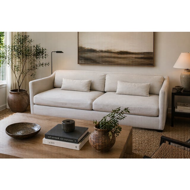 A generously scaled Cisco Home sofa in a soft neutral linen, featuring plush down-filled cushions and a relaxed, modern...