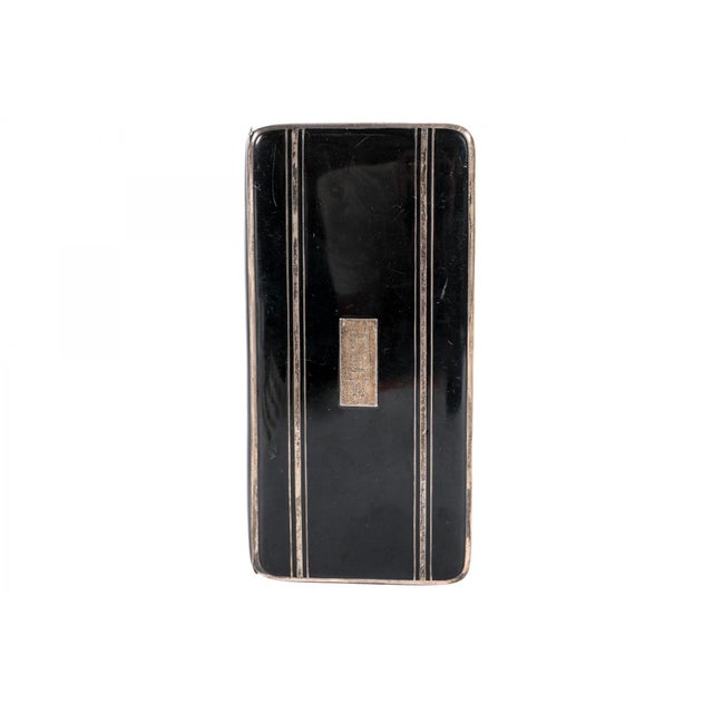 A sleek 1920s Art Deco rectangular cigarette case with a glossy black enamel finish, silver banded trim and interior,...