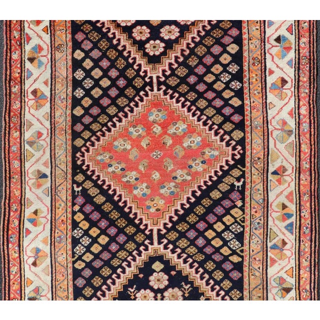 Measures: 4'9 x 9'2. This antique Persian Shiraz rug has been hand-knotted in wool and features a sub-geometric tribal...