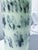 This work of glass art is a light teal layered glass with drawings of people silhouetted in navy blue made using the Graal...