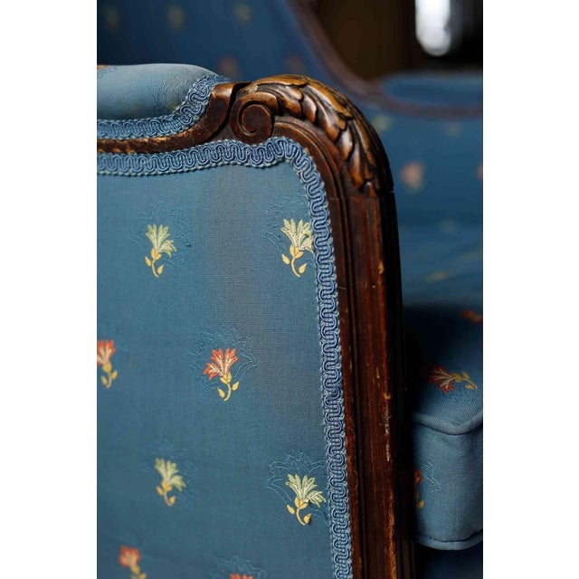 Antique French Louis XVI style bergère armchair. Carved detail with blue floral upholstery.