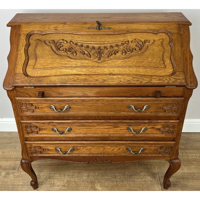A stunning Vintage French secretaire bureaux cabinet crafted from oak, featuring elegant carved detailing, graceful...