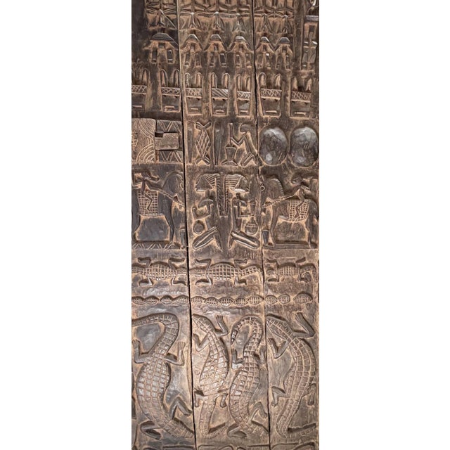 This vintage Dogon granary door from Mali features intricate carved relief figures—horses, crocodiles, and standing Nommo...