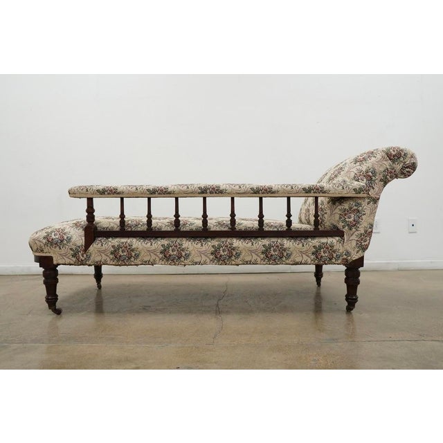 This vintage Victorian-style chaise lounge features a graceful, asymmetrical silhouette with a gently scrolled back and an...