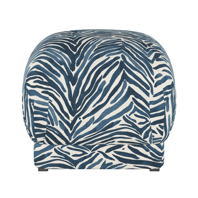 Smooth upholstery covers a sleek cushioned silhouette, accentuated at the corners with delicate handcrafted pleating. The...