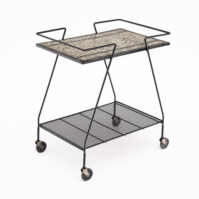 A distinctive French bar cart with a graphic tiled top set within a black tubular metal frame. The sculptural lines,...