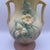 Cheerful pale yellow vase with handles decorated with flowers in high relief. The base is earthy pink Hull Art USA mark